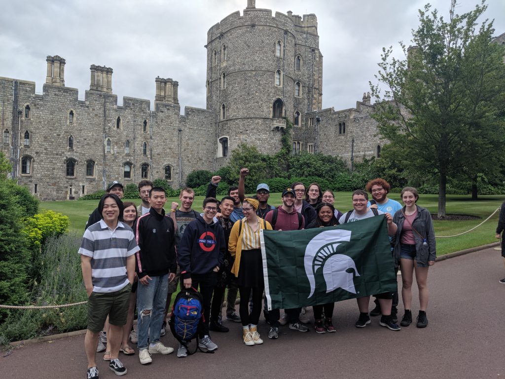 Group of students posing with Spartan flag in front of Windsor Castle
